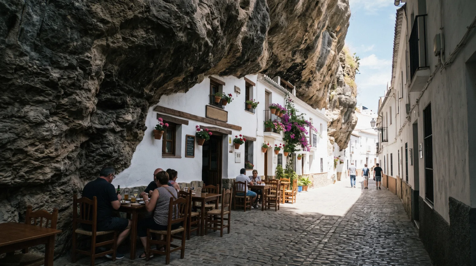 Whitewashed houses built under the rock overhang along the river street of Setenil de las Bodegas