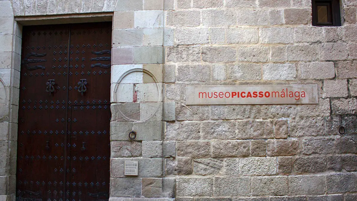 Guide with a yellow umbrella leading visitors into the Picasso Museum courtyard, Picasso Museum guided tour with skip-the-line ticket in Málaga