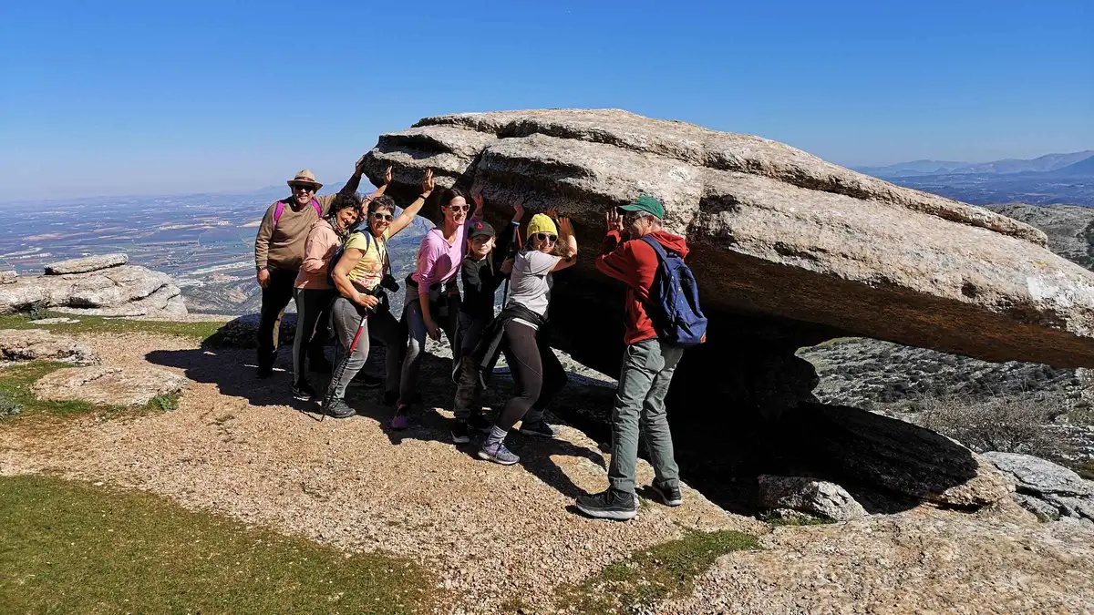 Guide pointing out fossil-bearing limestone on the Ammonites Route at El Torcal de Antequera, a hike near Málaga