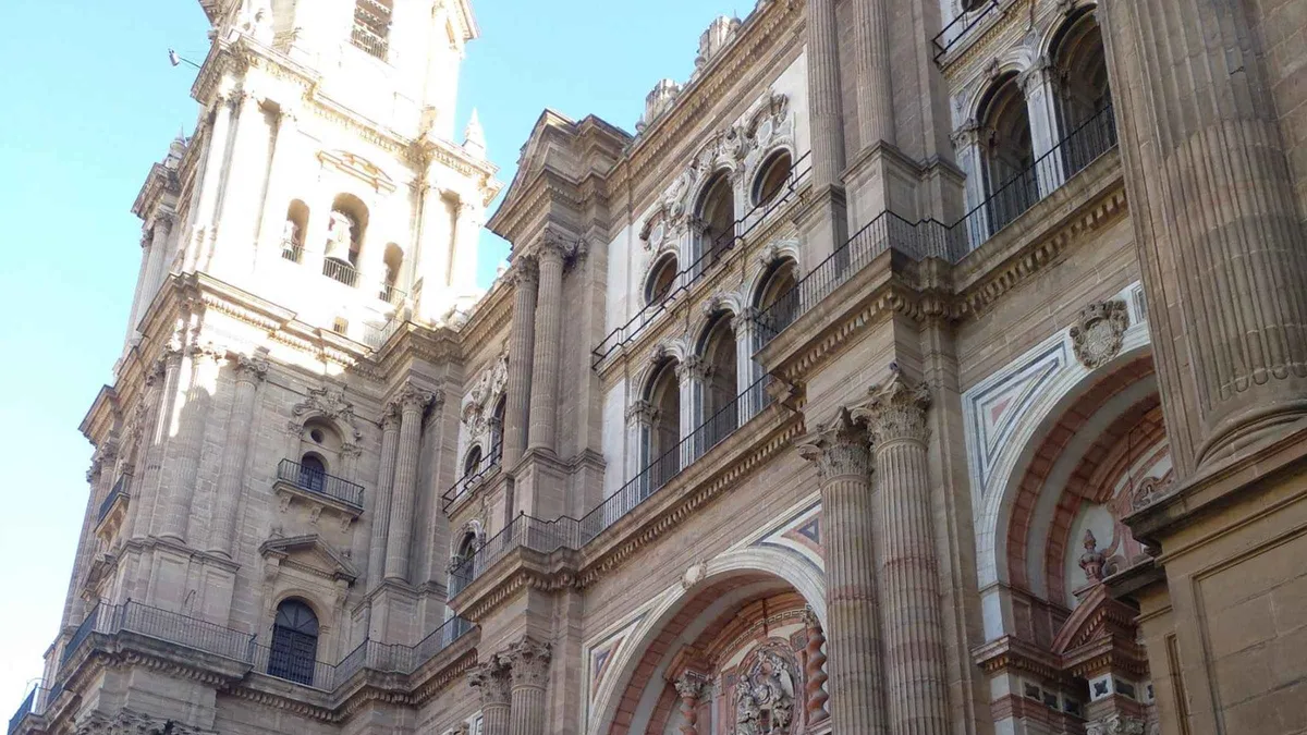Guide pointing out the unfinished tower of Málaga Cathedral to a six-person group, old town walking tour with Cathedral and Picasso Museum in Málaga