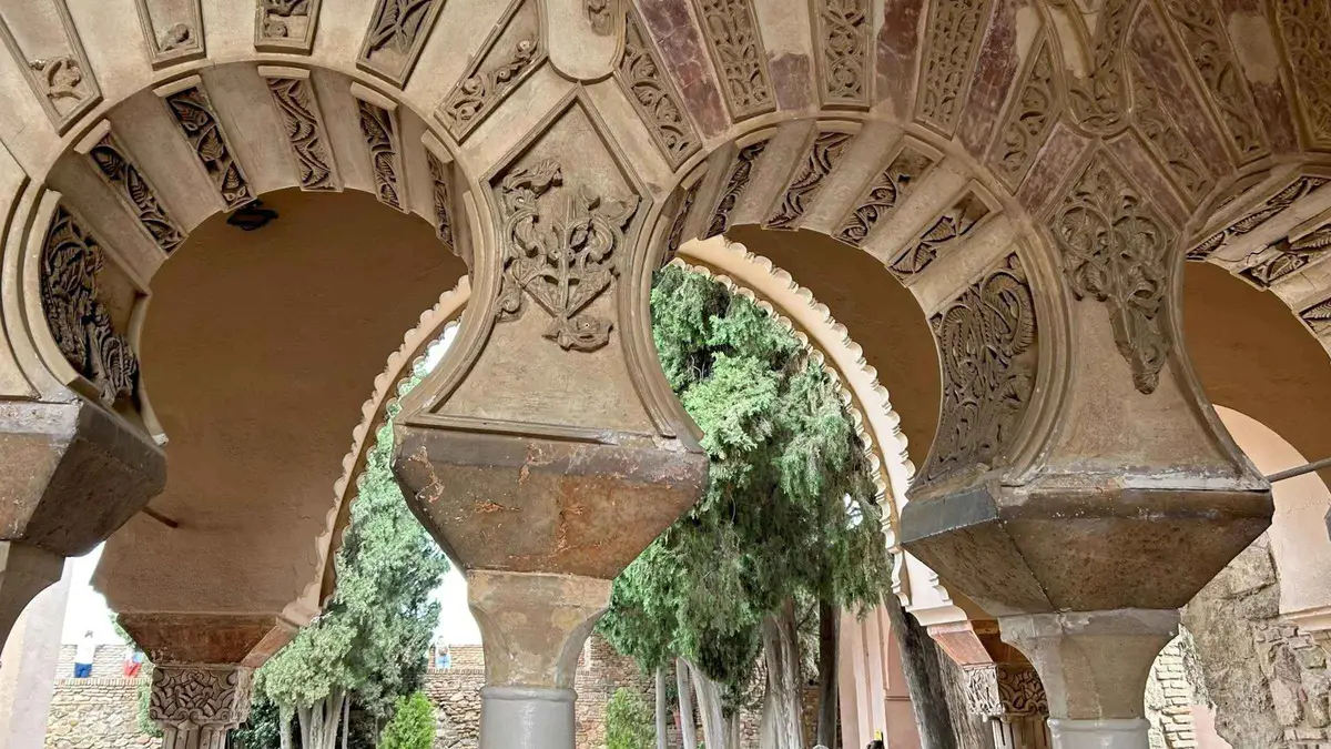 Guide with an orange umbrella beside the glass pyramid on Calle Alcazabilla, Alcazaba and Roman Theatre highlights tour in Málaga