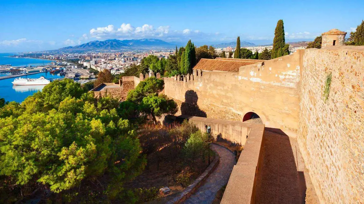 Visitor with headphones on the Gibralfaro walls looking over the port, Alcazaba and Gibralfaro Castle entry with audio guide in Málaga