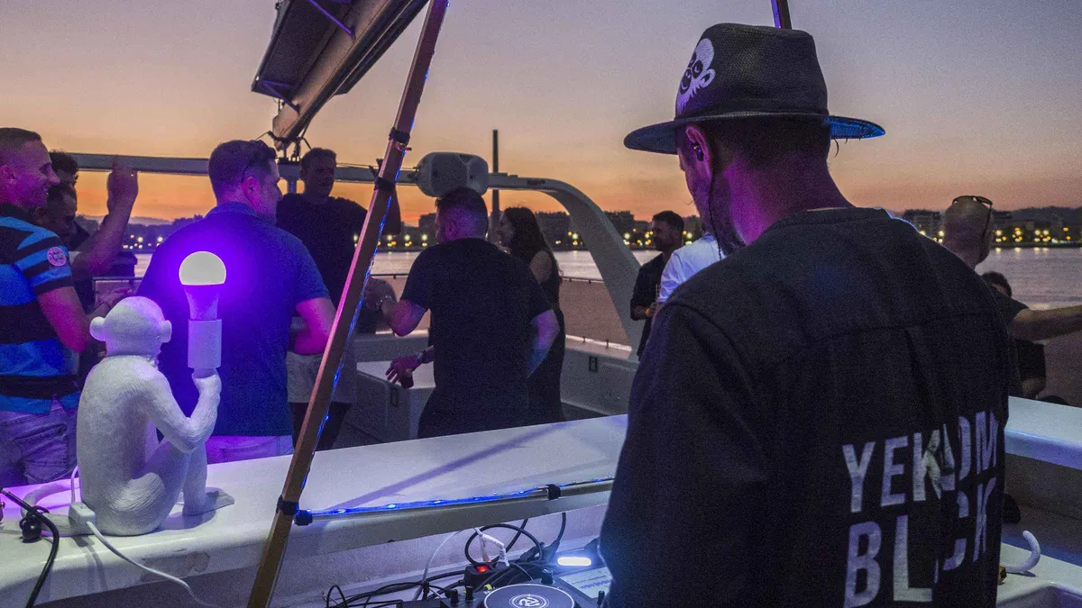 DJ and passengers with cava on a catamaran night cruise off Muelle Uno in Malaga